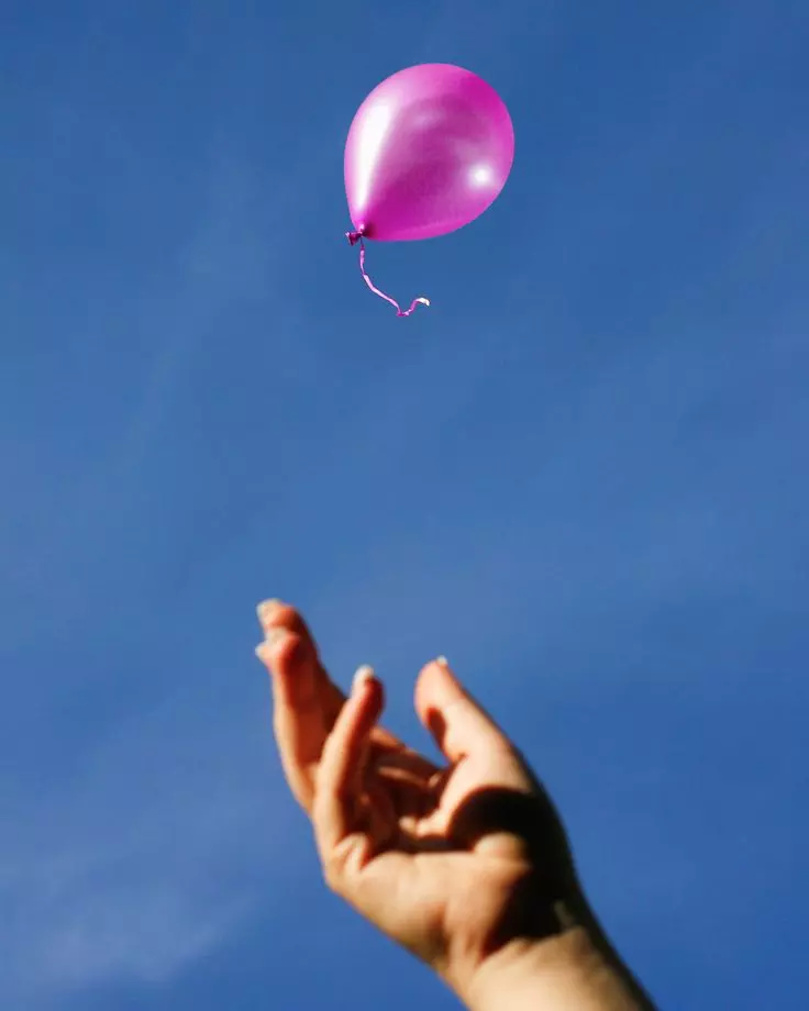 mano saltando globo al cielo